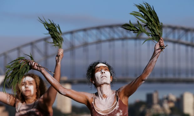 two women conduct an aboriginal ceremony in front of the sydney harbour bridge